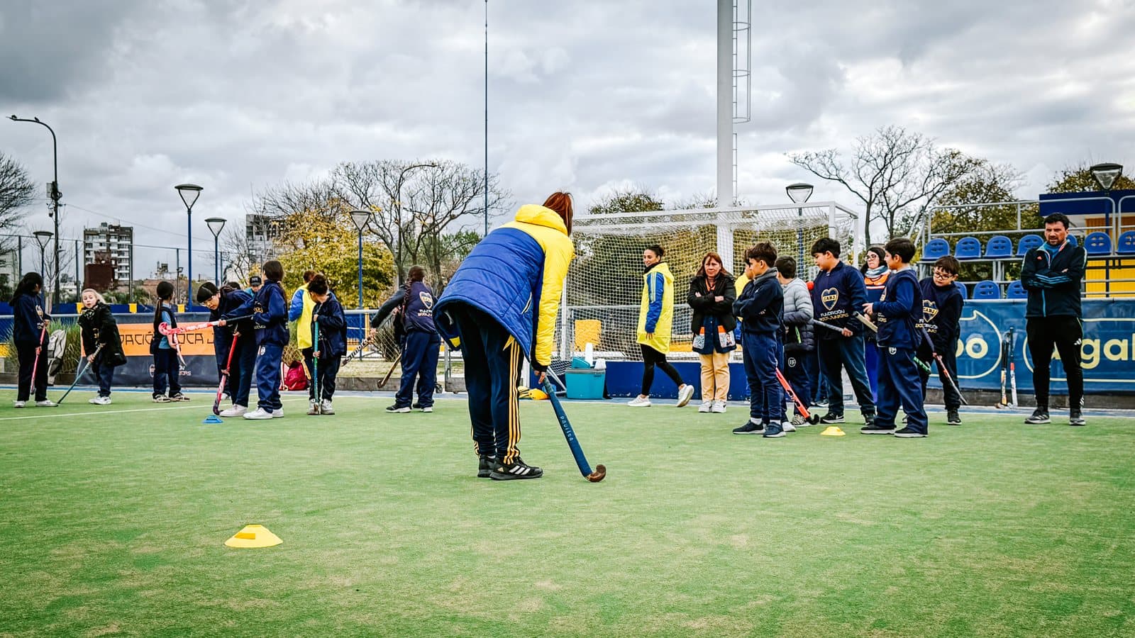 Chicos y chicas jugando al hockey en la cancha del club durante la clínica
