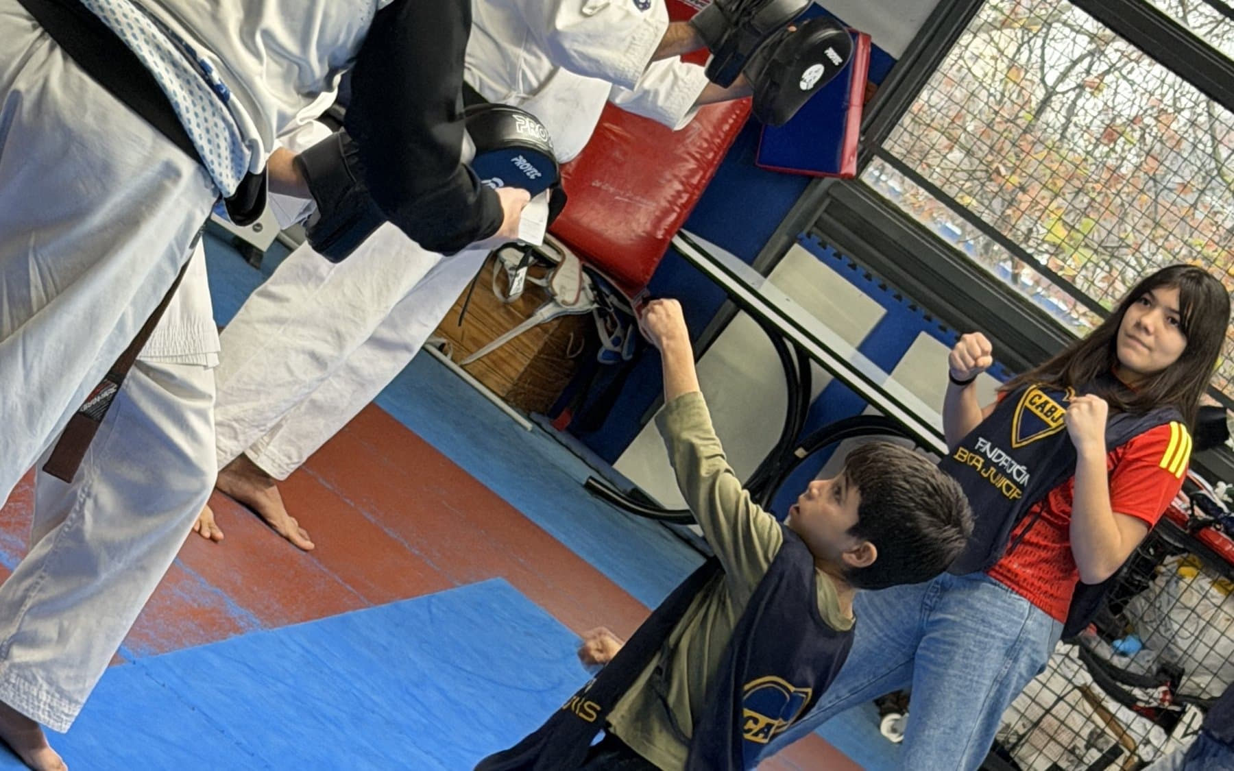 Un chico golpea el guante que le sostiene el profesor durante la clínica de karate, sobre el tatami