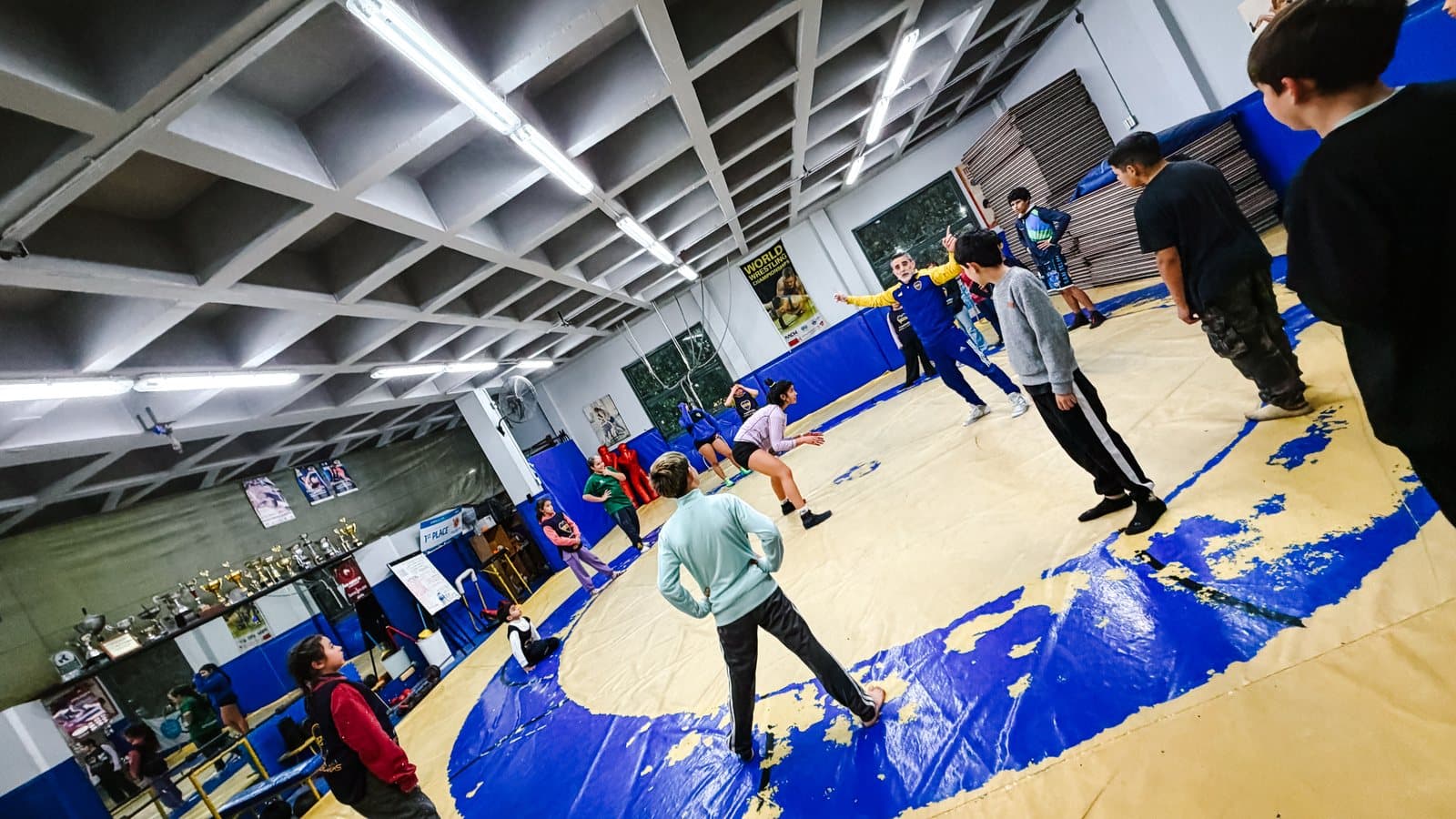 Participantes de la clínica de lucha sobre el tatami del club