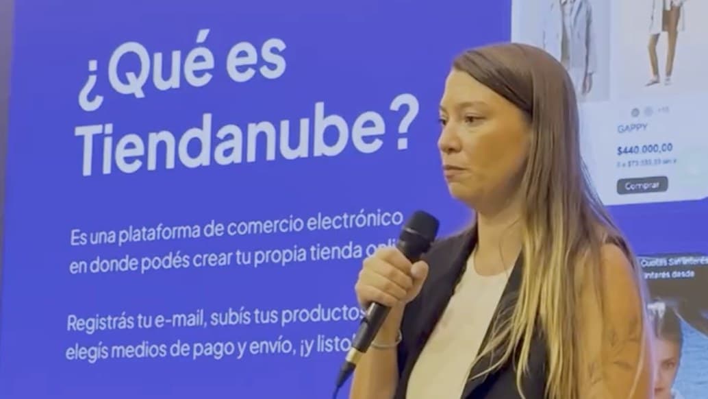 La expositora de Tiendanube habla con micrófono frente a una placa que pregunta "¿Qué es Tiendanube?"