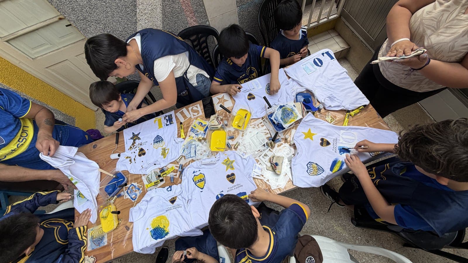 Vista desde arriba de los chicos y chicas pintando camisetas blancas extendidas en el piso